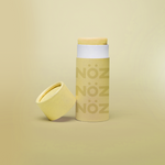 Load image into Gallery viewer, Yellow Nöz sunscreen stick with cap off, tilted against base of stick. All against a pale yellow gradient background. 
