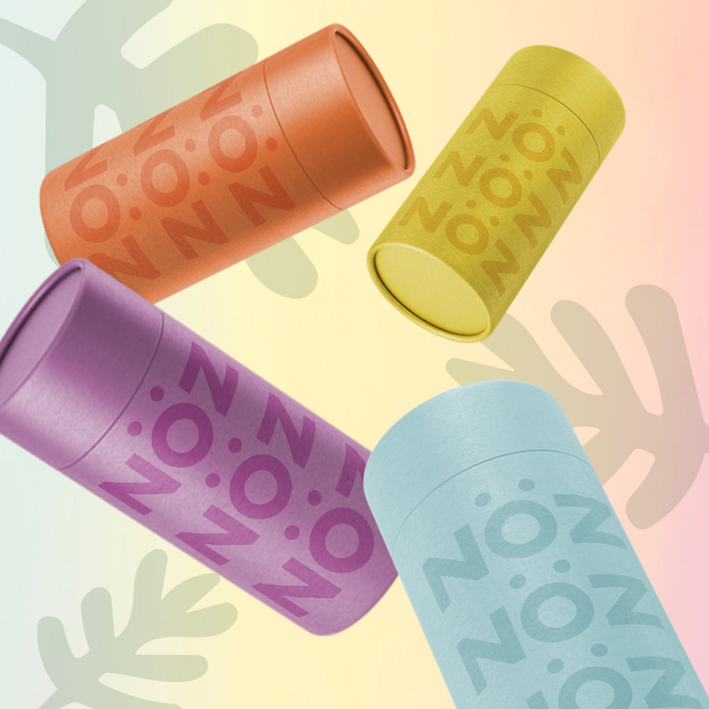 Four neon-colored Nöz sunscreen sticks with a pale, colorful gradient background and three grey plant leaf illustrations.